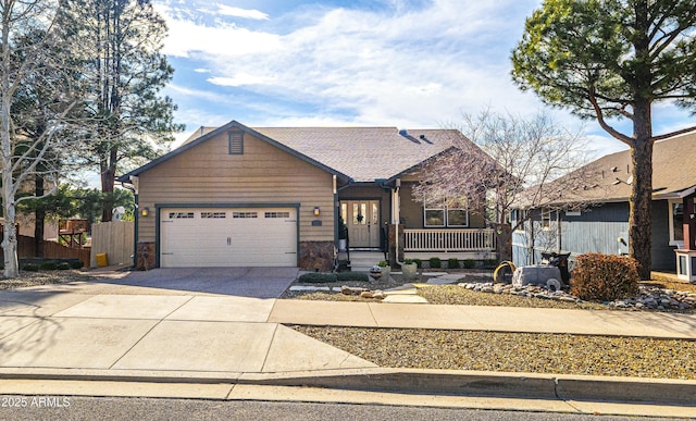 view of front of home featuring fence, stone siding, concrete driveway, an attached garage, and a porch