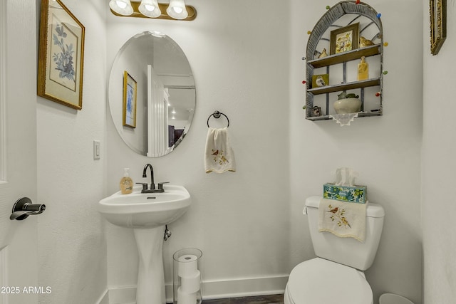 half bath featuring baseboards and toilet