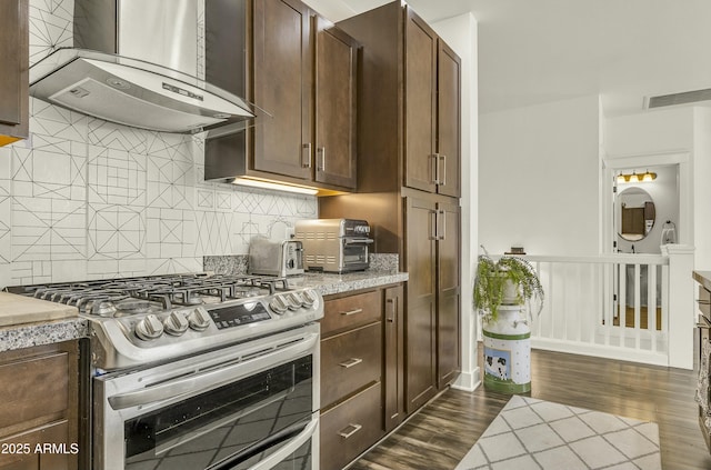 kitchen featuring wall chimney exhaust hood, double oven range, backsplash, visible vents, and dark wood-style floors
