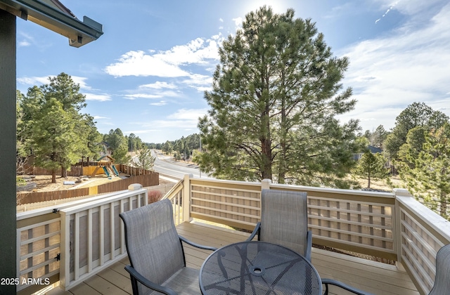 deck with a playground and outdoor dining area