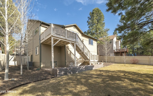 back of property featuring a lawn, a wooden deck, stairway, central AC, and fence