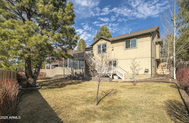 back of house featuring a lawn, fence, and stairs