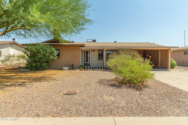 ranch-style house featuring a carport, concrete driveway, and brick siding