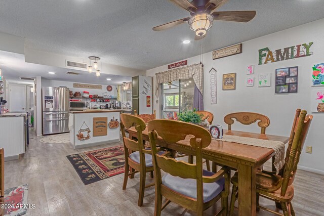 dining space with ceiling fan, light hardwood / wood-style floors, and a textured ceiling