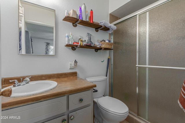 bathroom with vanity, a shower with shower door, and toilet