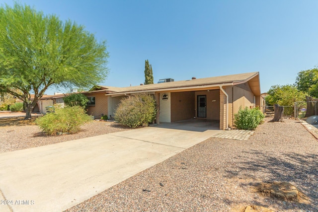 single story home with a gate, a carport, fence, concrete driveway, and brick siding