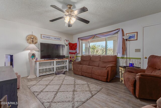 living room featuring ceiling fan, wood-type flooring, and a textured ceiling