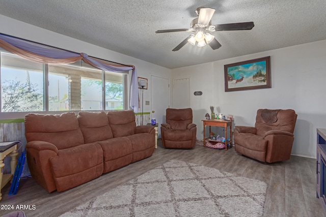 living room featuring a textured ceiling, light wood-type flooring, and ceiling fan