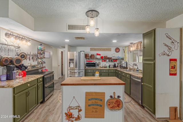 kitchen with appliances with stainless steel finishes, a textured ceiling, sink, light hardwood / wood-style flooring, and green cabinetry