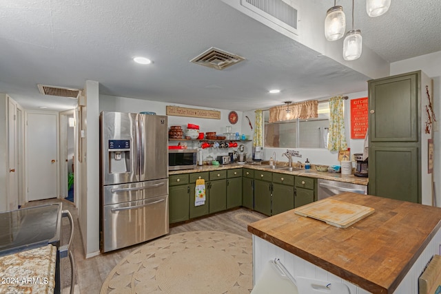 kitchen featuring sink, light hardwood / wood-style flooring, stainless steel appliances, and green cabinetry