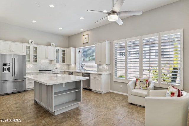 kitchen featuring ceiling fan, stainless steel appliances, white cabinetry, and a center island