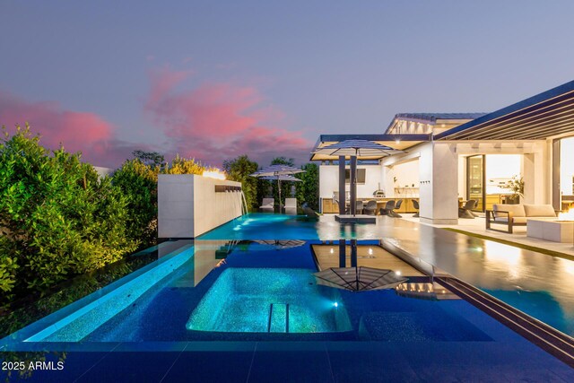 3684 E Boot Track Trl, Gilbert, AZ 85296 - pool at dusk with outdoor lounge area, an outdoor pool, a patio area, and an in-ground hot tub