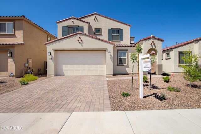 mediterranean / spanish-style home featuring a tiled roof, an attached garage, driveway, and stucco siding