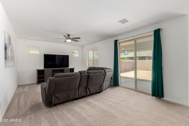 living room with a ceiling fan, baseboards, and light colored carpet