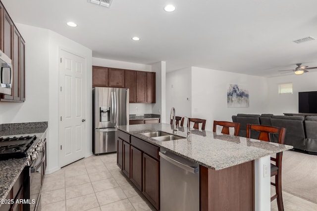 kitchen with a kitchen bar, visible vents, appliances with stainless steel finishes, a sink, and open floor plan