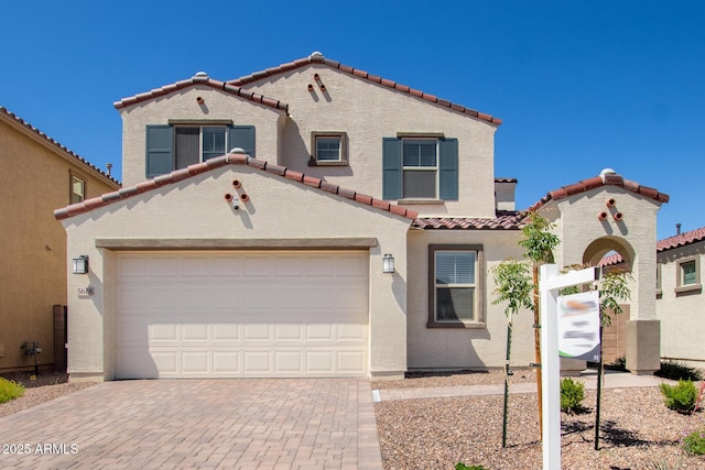 mediterranean / spanish house featuring stucco siding, decorative driveway, and a tile roof