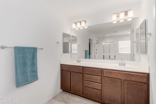 bathroom with double vanity, walk in shower, a sink, and tile patterned flooring