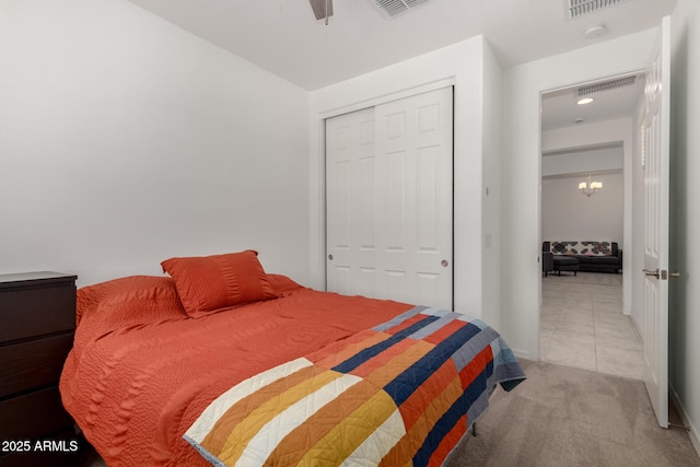carpeted bedroom featuring ceiling fan with notable chandelier, a closet, and visible vents