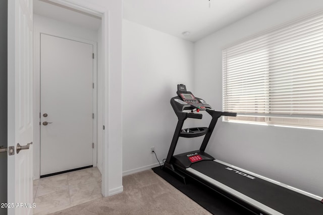 exercise room featuring baseboards and light colored carpet