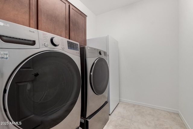 laundry room with separate washer and dryer, cabinet space, and baseboards