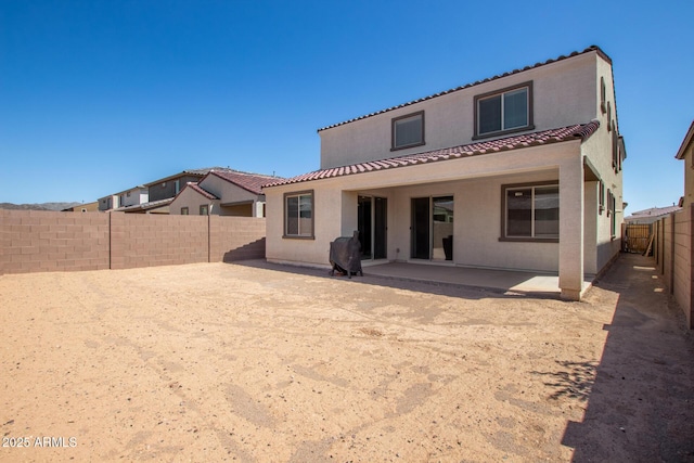 rear view of house with a tiled roof, a patio, a fenced backyard, and stucco siding
