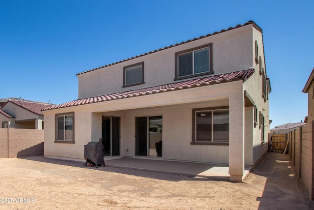 rear view of house featuring a fenced backyard, a patio area, stucco siding, and a tiled roof