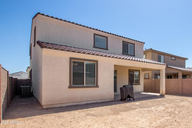 back of house featuring cooling unit, a fenced backyard, stucco siding, a patio area, and a tiled roof