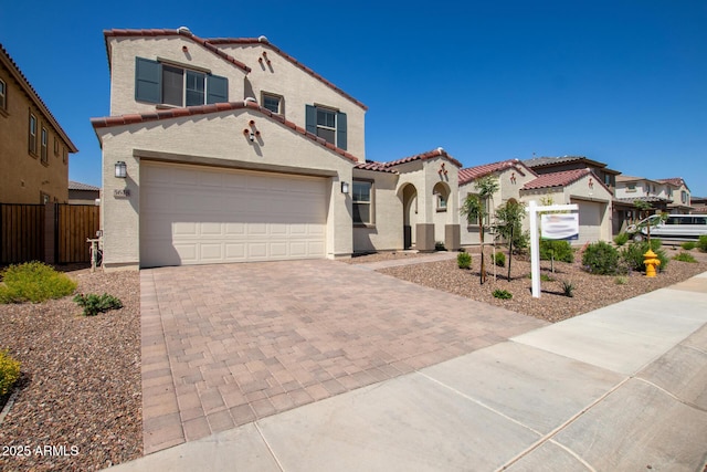 mediterranean / spanish home featuring fence, a residential view, stucco siding, decorative driveway, and a tiled roof