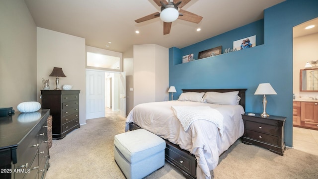 bedroom with ceiling fan, ensuite bath, and light carpet