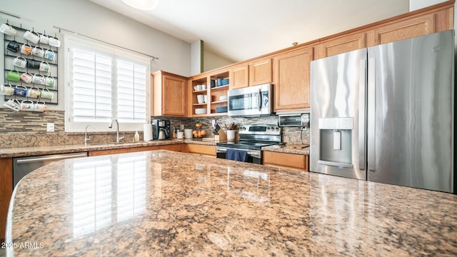 kitchen featuring light stone counters, sink, tasteful backsplash, and stainless steel appliances