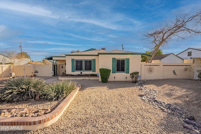 back of house with a gate, fence, and stucco siding