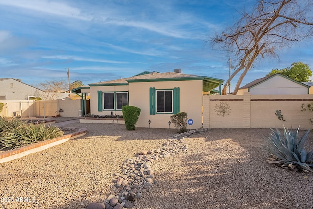 rear view of property with fence, a gate, and stucco siding