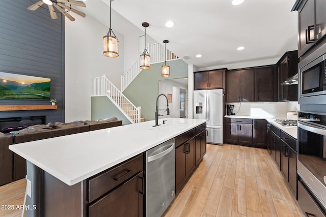 kitchen featuring sink, hanging light fixtures, a kitchen island with sink, light hardwood / wood-style floors, and stainless steel appliances