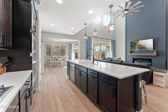 kitchen featuring sink, dishwasher, an island with sink, pendant lighting, and light hardwood / wood-style floors