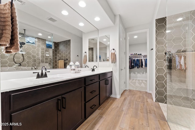 bathroom with vanity, tiled shower, hardwood / wood-style floors, and tile walls