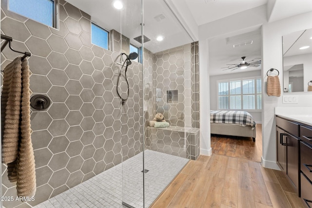 bathroom featuring hardwood / wood-style flooring, vanity, a tile shower, and ceiling fan