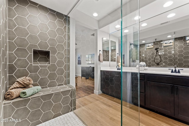 bathroom featuring tile walls, vanity, tile patterned flooring, and a tile shower