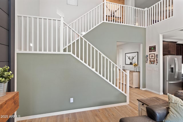 stairway featuring a towering ceiling and wood-type flooring