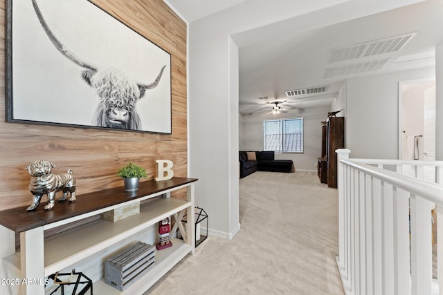 hall featuring light carpet and wood walls