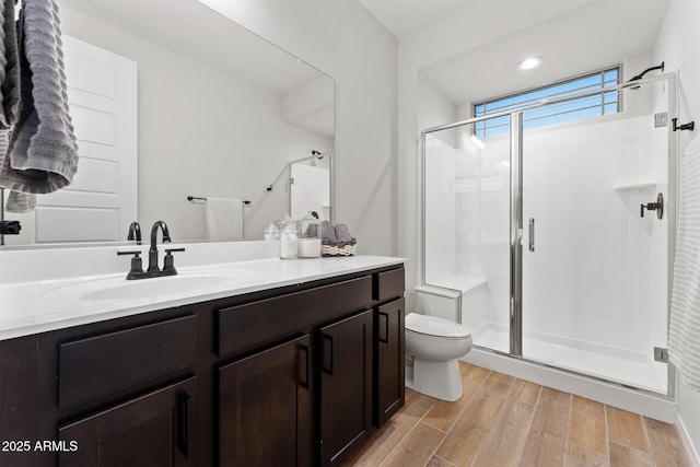 bathroom featuring vanity, toilet, and a shower with door