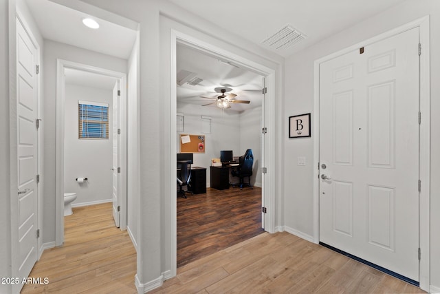 foyer entrance with ceiling fan and light wood-type flooring