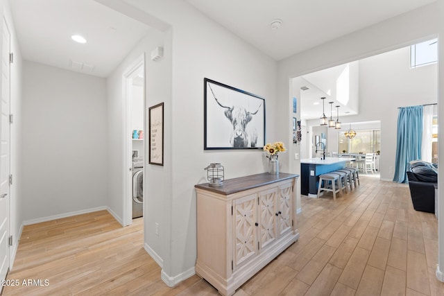 corridor featuring sink, washer / dryer, and light hardwood / wood-style floors