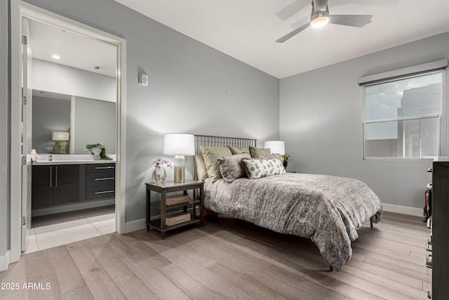 bedroom featuring light wood finished floors, visible vents, ceiling fan, baseboards, and ensuite bathroom