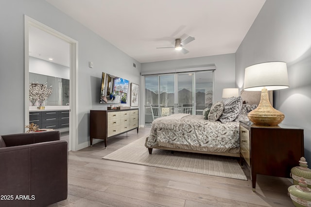 bedroom with ensuite bathroom, light wood-type flooring, and a ceiling fan