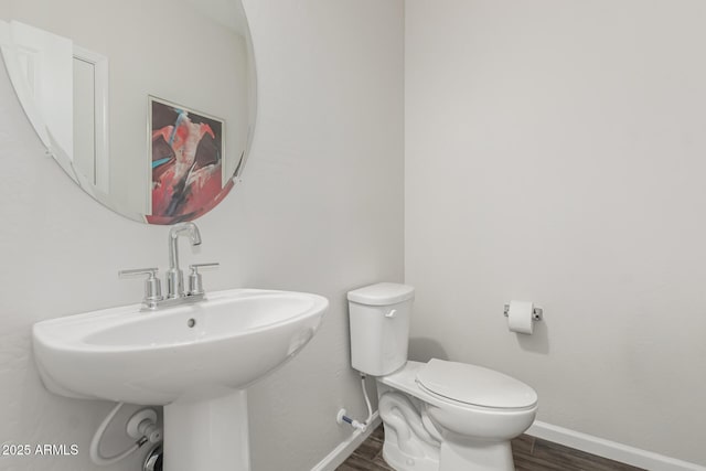 bathroom with a sink, wood finished floors, toilet, and baseboards