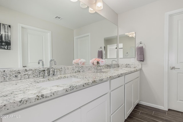 bathroom with wood tiled floor, visible vents, a sink, and double vanity