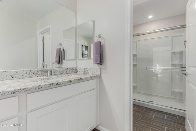 full bathroom featuring a stall shower, wood finish floors, vanity, and baseboards