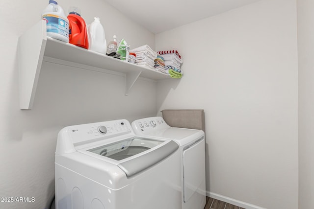 laundry area with laundry area, baseboards, washer and clothes dryer, and wood finished floors