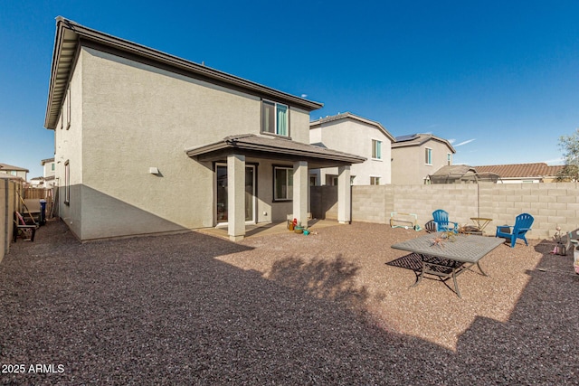 back of property featuring an outdoor fire pit, a fenced backyard, a patio area, and stucco siding