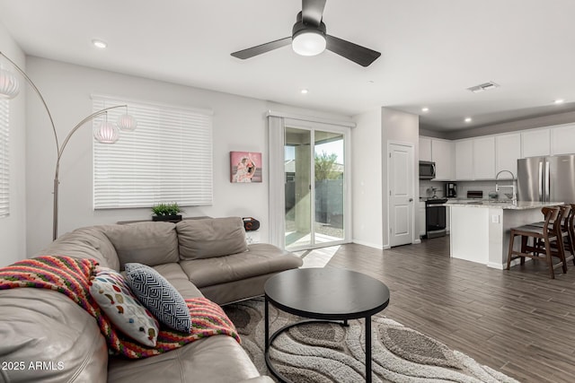 living area with ceiling fan, visible vents, dark wood-type flooring, and recessed lighting